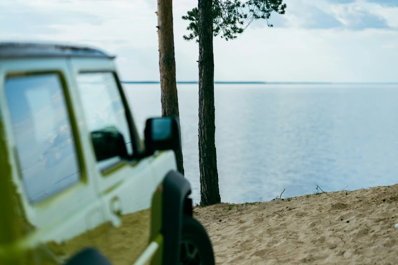 a jeep is parked in the sand by water