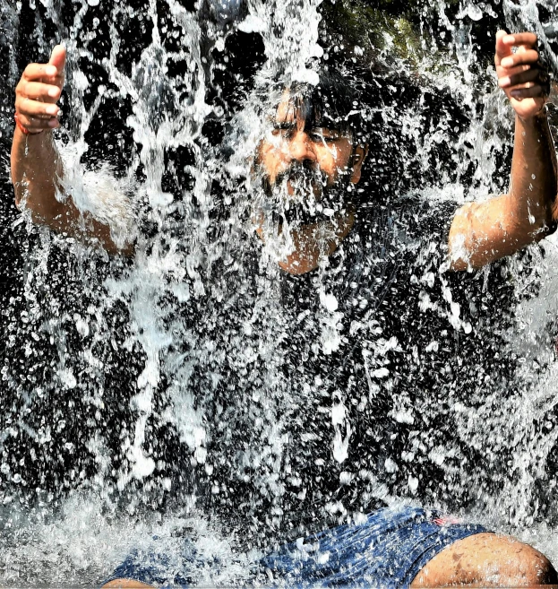 a person laying down in a body of water holding a camera