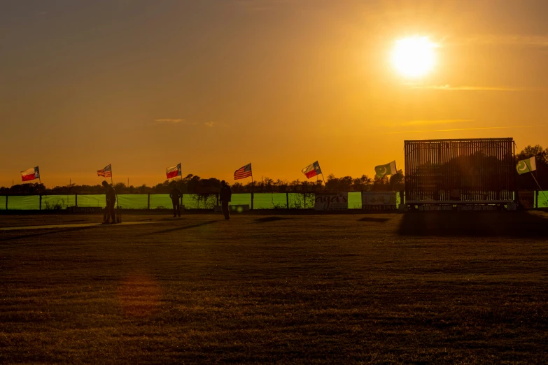 a view of a fence and a sunset with american flags