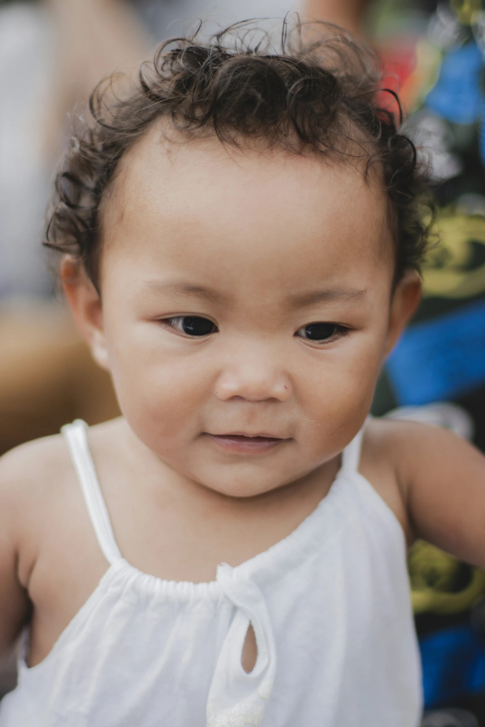 a little baby wearing white clothes standing next to a person