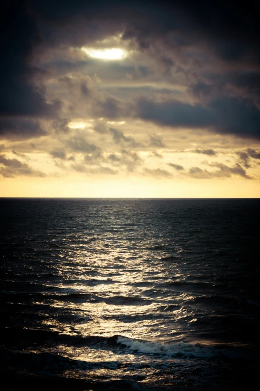 an ocean with some clouds above the water