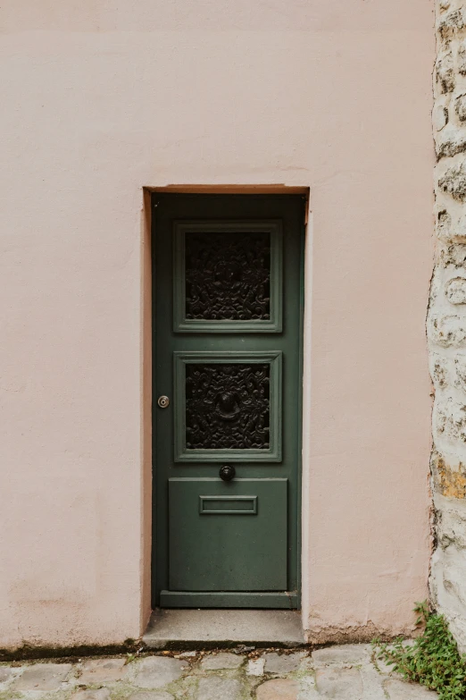 the door is in the pink wall with a green door