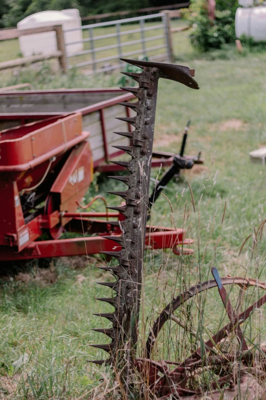 a plow next to a rusted wheel in a field