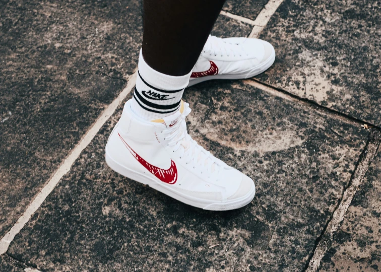 a person in white sneakers is standing on the pavement