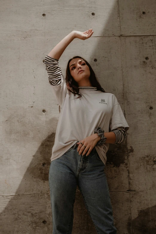 a girl leans against a concrete wall with her hand outstretched