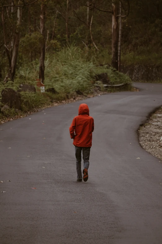 a man walks down the road in the rain