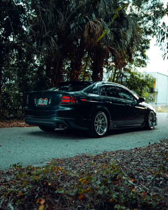 a black car parked on the side of the road next to trees