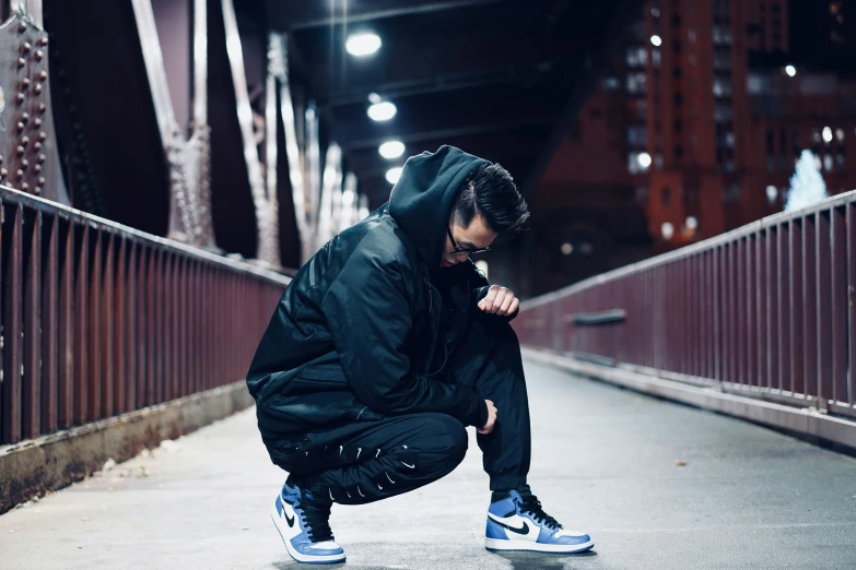 a man in black jacket kneeling down on cement