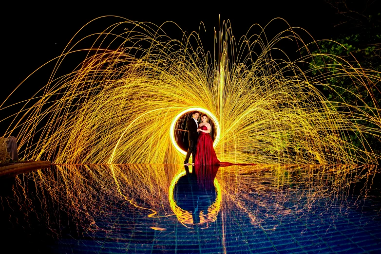 a woman in red shirt and skirt standing under a firework sculpture
