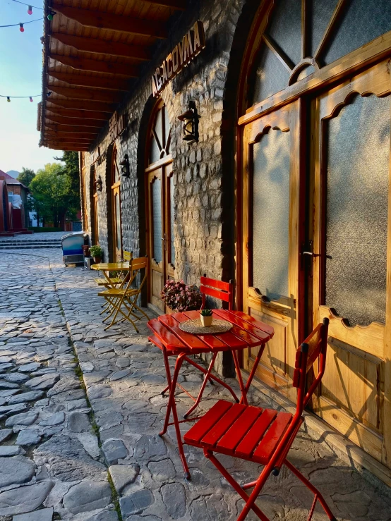 red tables and chairs outside of a stone building