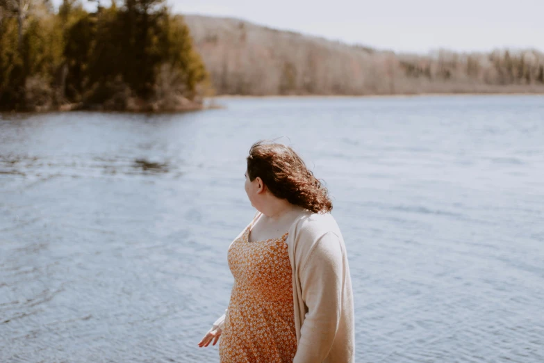 a woman in a long yellow dress looking over the water