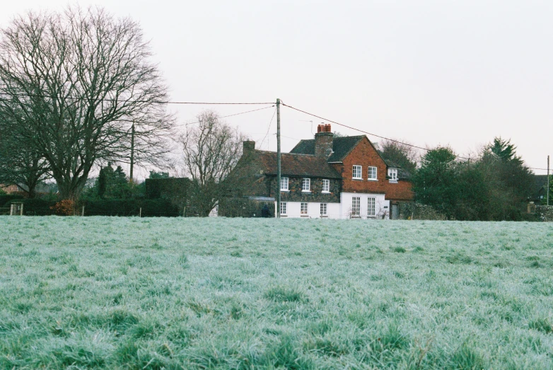 a very large, big house behind a lush green field