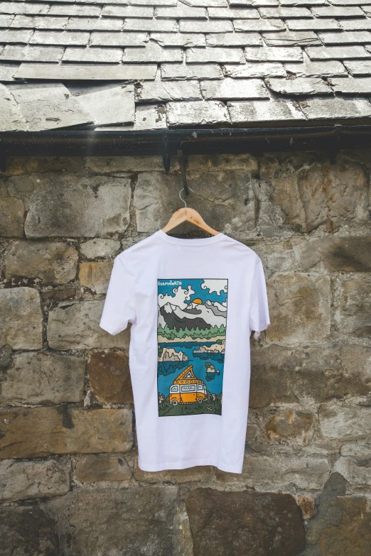 t - shirt hanging against a stone wall with a car parked in the water