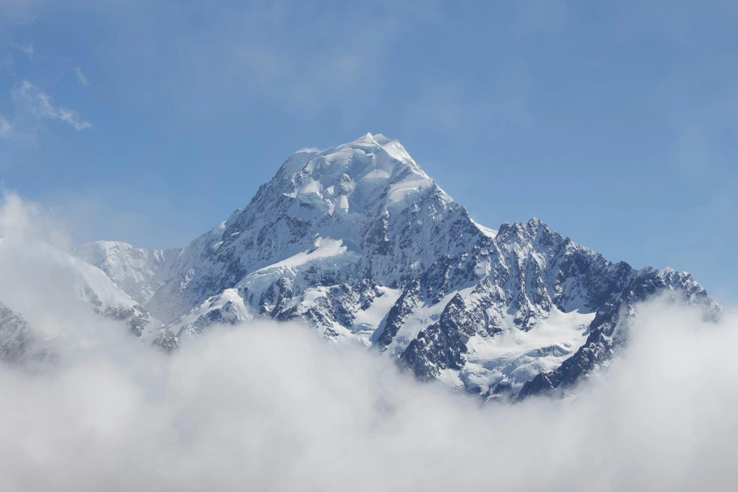 a mountain with snowy peaks in the clouds