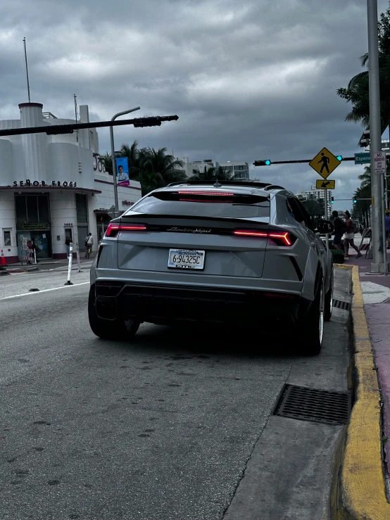 an elegant car in front of a building and traffic lights on a dark street