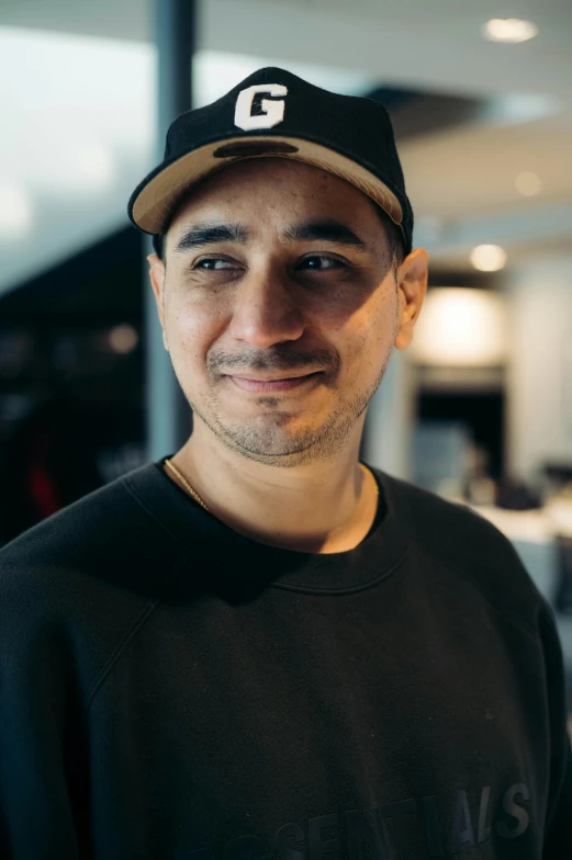 a man is smiling and wearing a cap