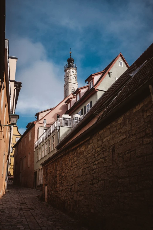 a narrow street between two building with an old clock tower on top