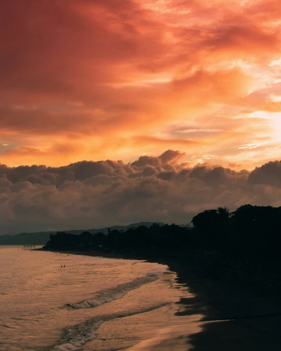 a sunset over water and tree's at the edge