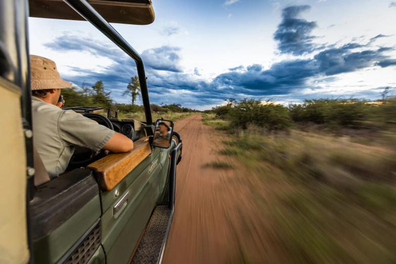 a man in a safari vehicle watching another man in a jeep