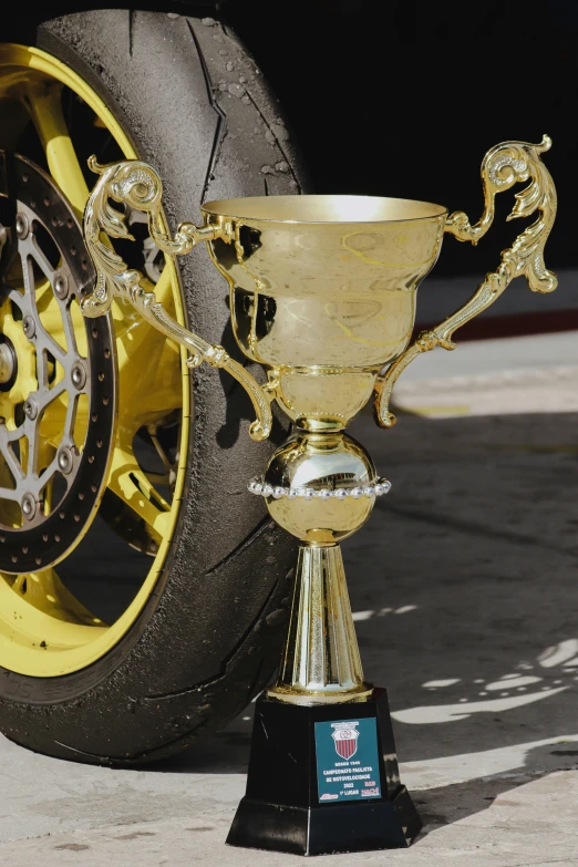 gold trophy standing on top of black stand next to a motorcycle