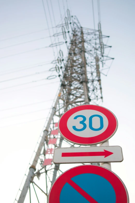 a large high voltage power pole with signs showing the number 30 and a no right turn sign above it