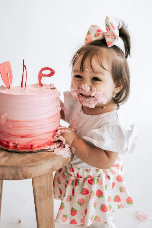 little girl eating birthday cake from a wooden table