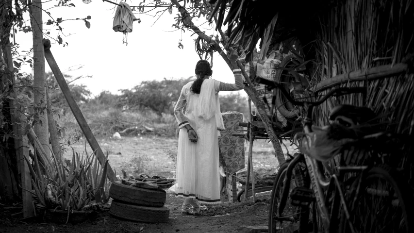 a woman in white dress standing under a thatched roof