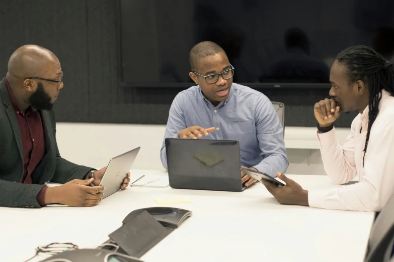 three people looking at a laptop while on a meeting