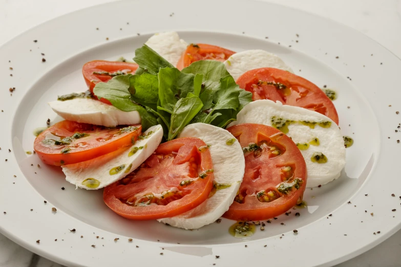 a plate has tomatoes, mozzarella and basil