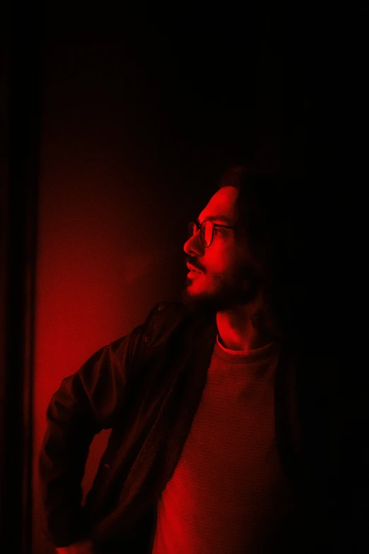 a man stares while wearing a black jacket and a red light