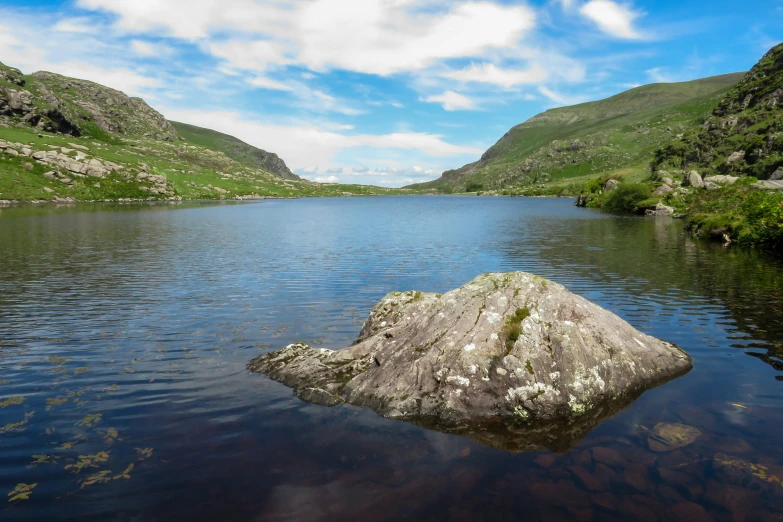 a large rock sitting in the middle of a lake