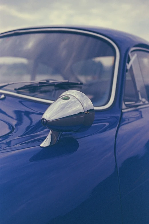 an old blue car with a side mirror