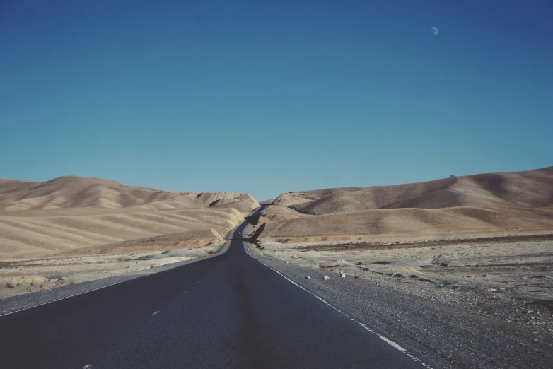 a view looking down an empty road in the middle of desert