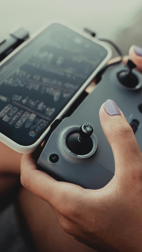 a hand holding a smart phone and game controller