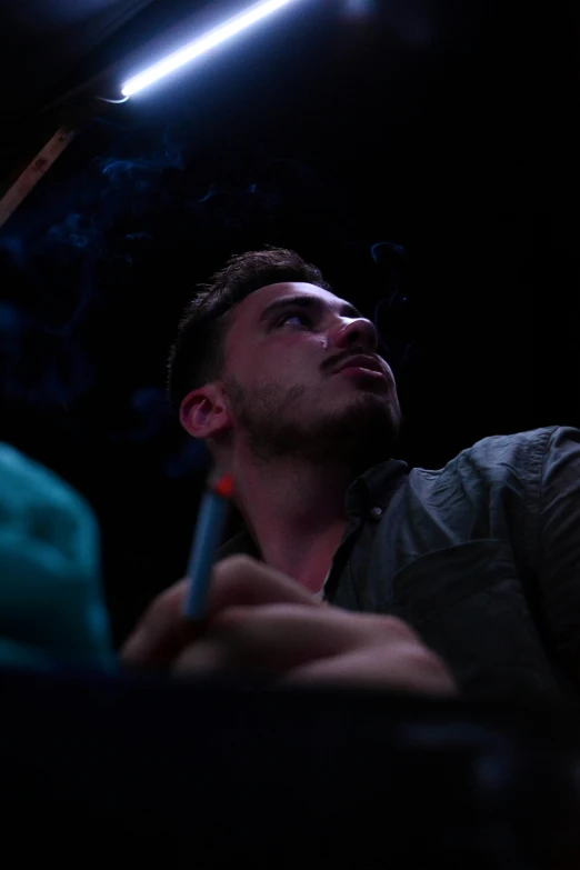 a young man smoking in the dark while sitting down