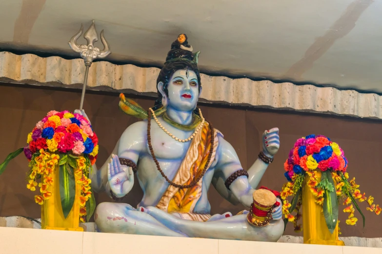 the statue is surrounded by flowers on the shelf