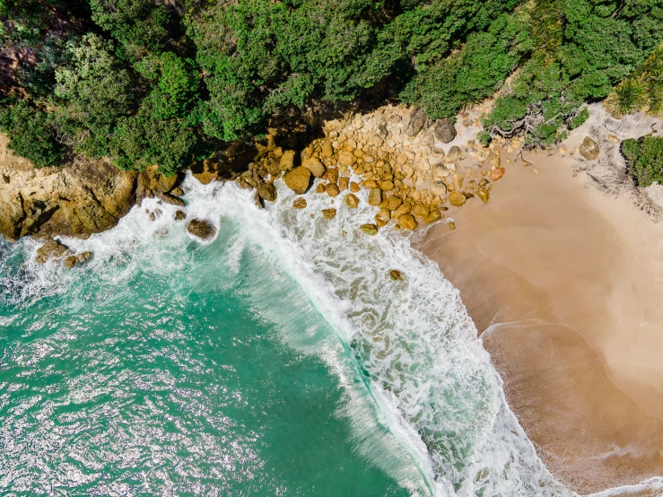 an overhead view of a beach and ocean with waves