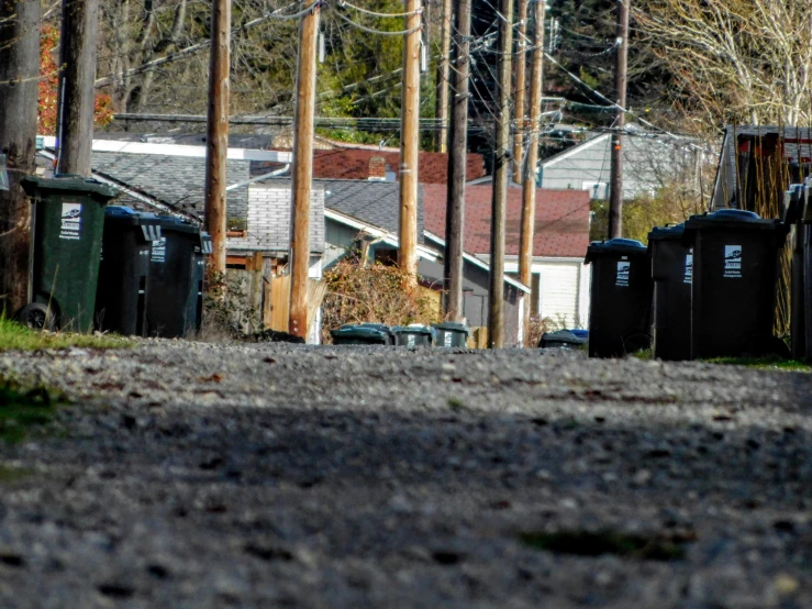 a gravel road covered in trash bins and poles