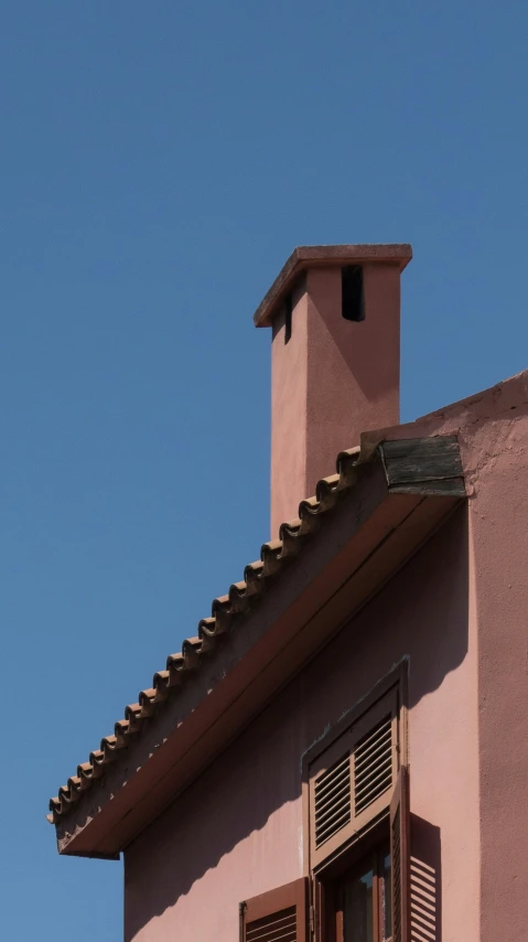 the top part of a pink building has two large open windows