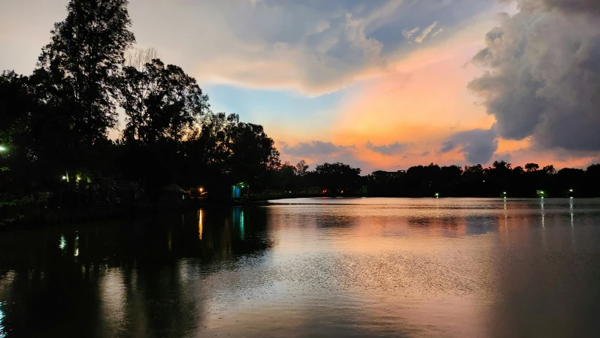 some trees are around some water at sunset