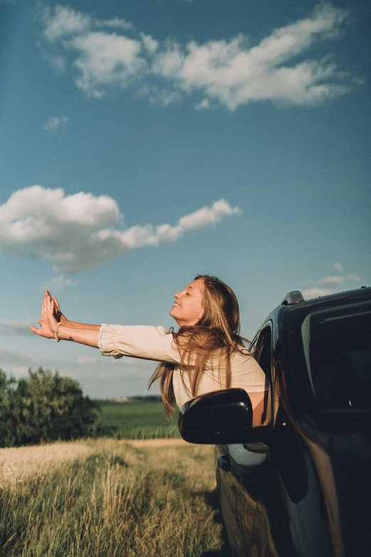 a girl leans out of her vehicle in the countryside