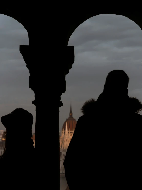 man in fur coat looking out at a view of a large cathedral