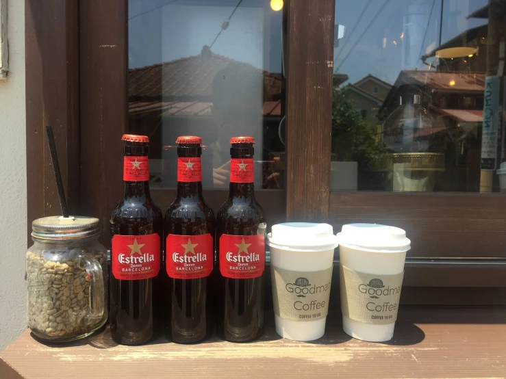 three cups sitting on the ledge of a building next to two empty jars