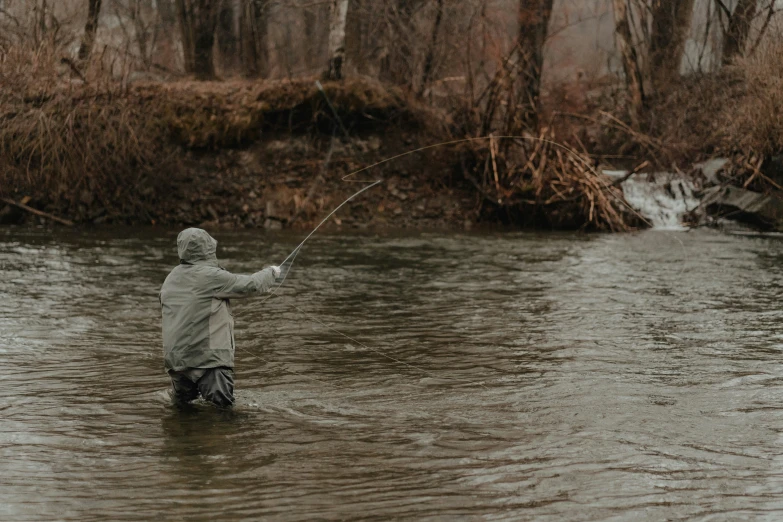 a person wading through a stream in the middle of winter