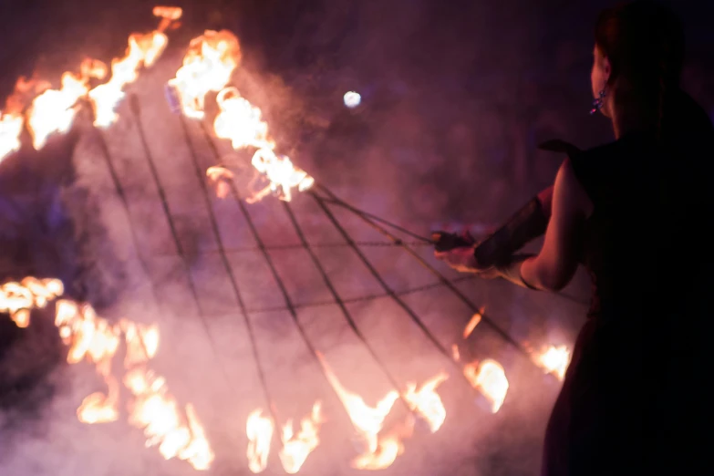 a woman in black dress holding torches while standing