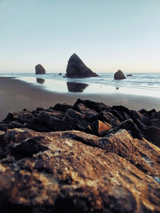 three rocks are at the edge of the water