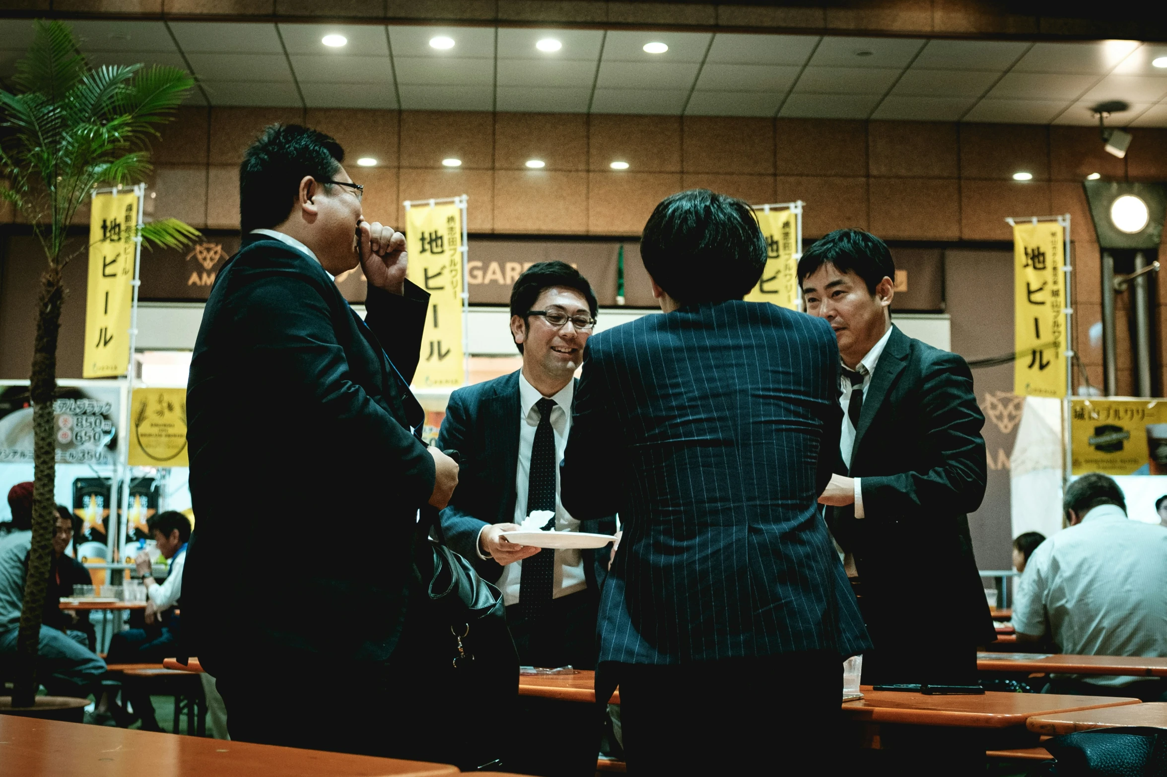 four business men standing around each other in a room