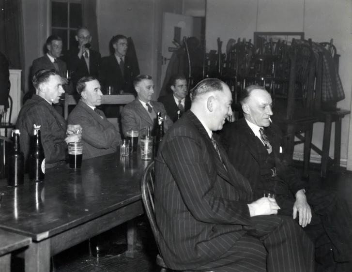 many men sitting at a long table drinking beer