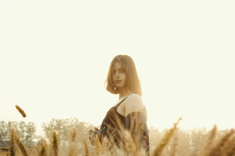 the girl stands in tall grass near a bird flying over her head