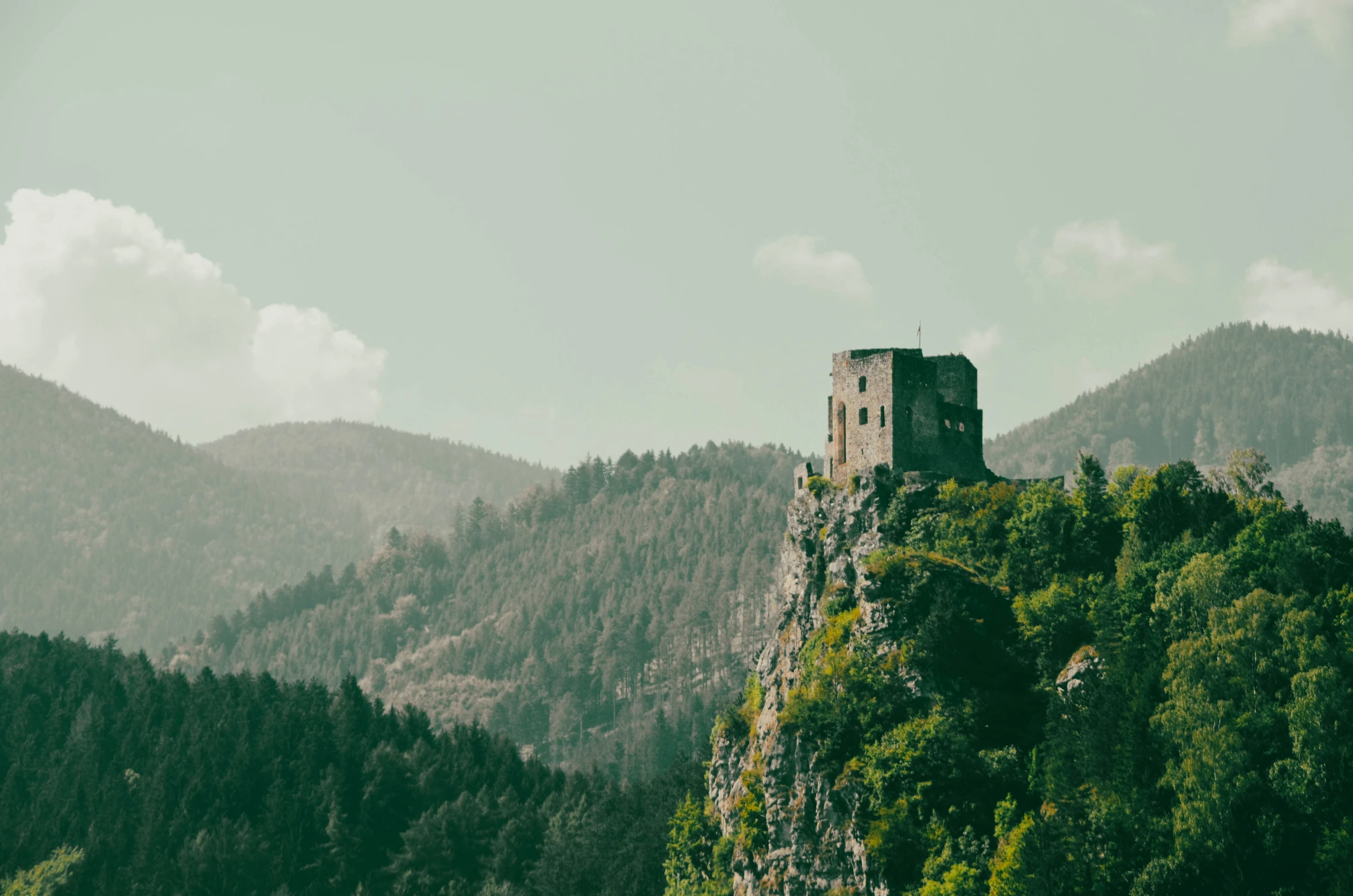 an old, abandoned tower in the middle of trees on top of a mountain